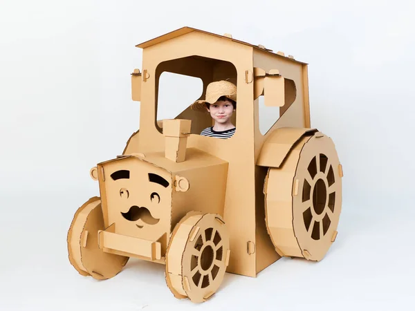 Маленький мальчик играет с картонным трактором на белом фоне. Концепция сельского хозяйства Макет для дизайна с копировальным пространством. — стоковое фото