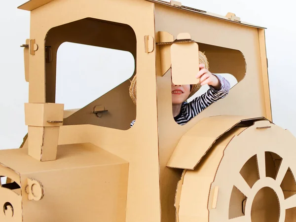 A little boy is playing with cardboard tractor on a white background. Agriculture concept. Mockup for design with copy space. — Stock Photo, Image