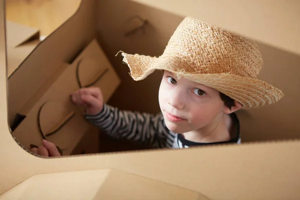 Ein kleiner Junge spielt mit einem Traktor aus Pappe auf weißem Hintergrund. Landwirtschaftskonzept. Mockup für Design mit Kopierraum. — Stockfoto