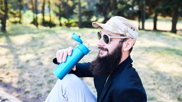 Uomo barbuto che beve caffè nel bosco dopo il lavoro — Foto Stock