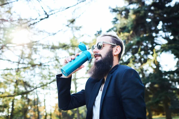 Uomo barbuto che beve caffè nel bosco dopo il lavoro — Foto Stock