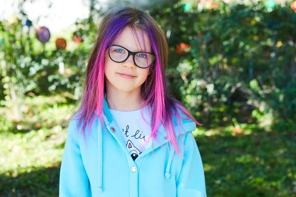 Beautiful portrait of a girl 8 years old with pink hair in the garden in summer. — Stock Photo, Image