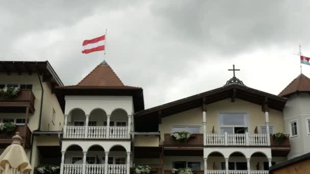 雲の中にオーストリアの有名なAchenseeの近くの高級ホテルの上にオーストリアの旗を吹いて 静的ワイドショット ストック動画