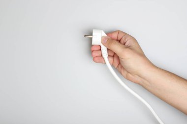 hafif bir arka plan üzerinde elinde elektrik fişi