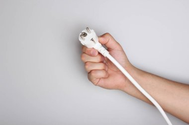 hafif bir arka plan üzerinde elinde elektrik fişi