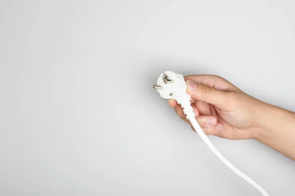 electric plug in hand on a light background