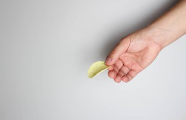 hafif bir arka plan üzerinde elinde patates cipsi