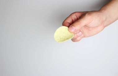 hafif bir arka plan üzerinde elinde patates cipsi