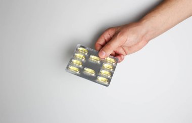 hafif bir arka plan üzerinde elinde kapsül blister