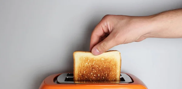 トーストと明るい背景にオレンジ色のトースターを手します — ストック写真