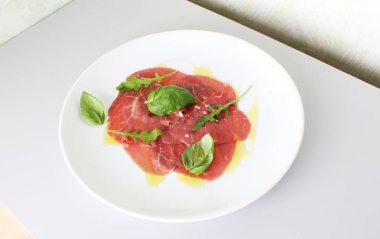 Dana carpaccio ışık gri fesleğen arka plan üzerinde