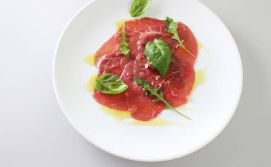 Dana carpaccio ışık gri fesleğen arka plan üzerinde