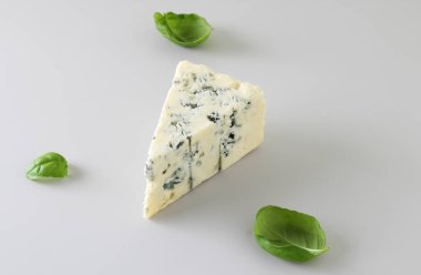 mavi peynir ışık gri fesleğen arka plan üzerinde bir parçası