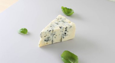 mavi peynir ışık gri fesleğen arka plan üzerinde bir parçası