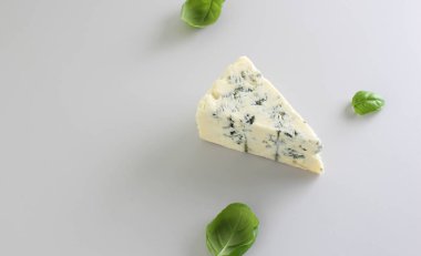 mavi peynir ışık gri fesleğen arka plan üzerinde bir parçası