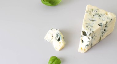 mavi peynir ışık gri fesleğen arka plan üzerinde bir parçası