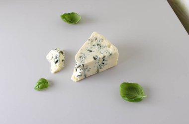 mavi peynir ışık gri fesleğen arka plan üzerinde bir parçası