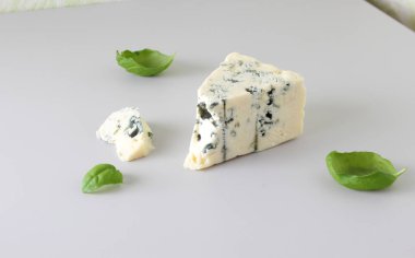 mavi peynir ışık gri fesleğen arka plan üzerinde bir parçası