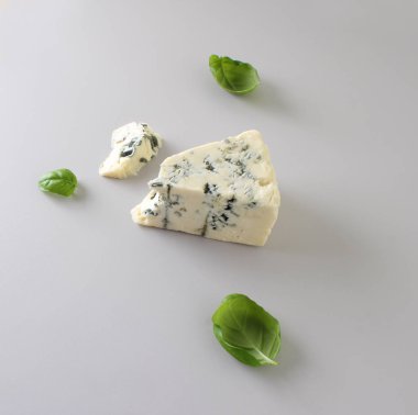 mavi peynir ışık gri fesleğen arka plan üzerinde bir parçası