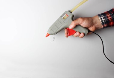 Gri arkaplanda tutkal tabancası olan el.