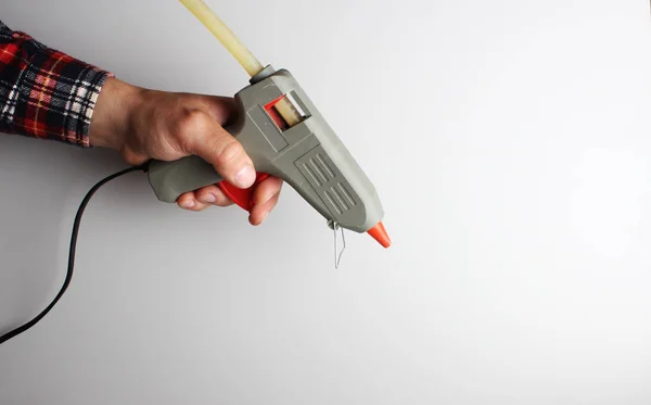Glue gun hand on a gray background — Stock Photo, Image