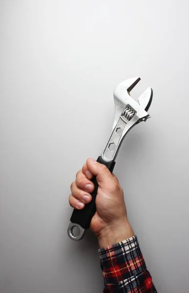 wrench in hand on a gray background