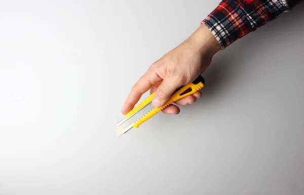 Cuchillo de oficina en la mano sobre un fondo gris — Foto de Stock