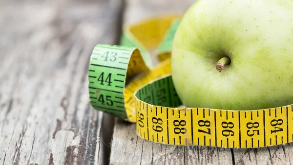 Weight loss, diet concept - green apple with tape measure, web b