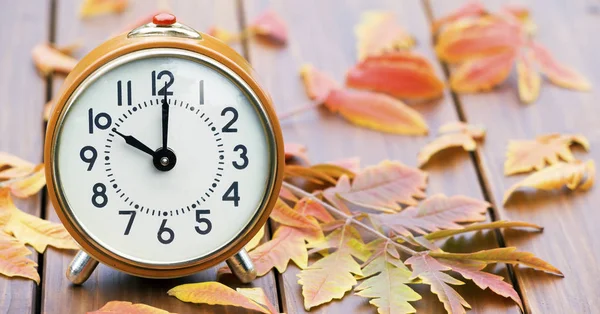Relógio de alarme retro com folhas de outono, horário de verão conc — Fotografia de Stock