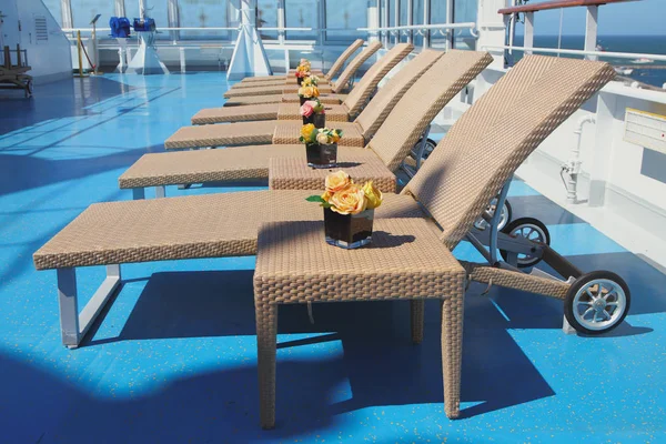 Sun beds and tables in lounge zone on deck of cruise liner