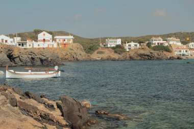 Deniz körfezi ve kayalık sahilde balıkçı köyü. Cala Mesquida, Menorca, İspanya