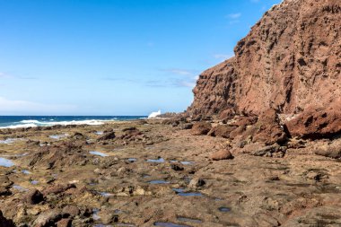 İspanya, Tenerife 'deki Bocinegro Dağı' nın kırmızı kayalıkları ile Atlantik Okyanusu kıyısı