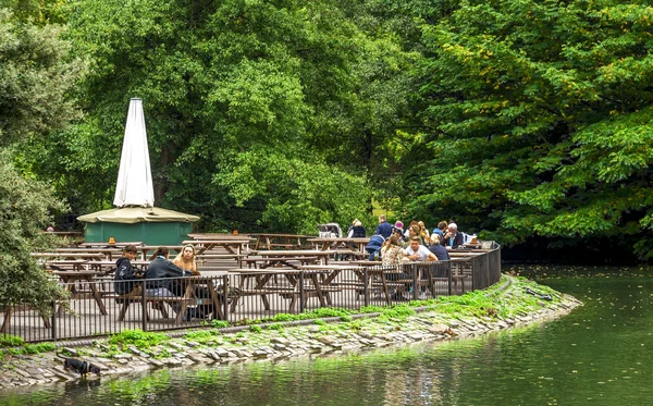 La gente almuerza en Pear Tree Café cerca de un pequeño lago en Battersea Park, Londres, Reino Unido — Foto de Stock