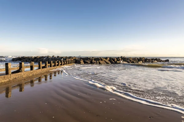 Ondas rompem uma pequena estrutura panorâmica de quebra-mar na praia da cidade de Aberdeen em um belo dia ensolarado, na Escócia — Fotografia de Stock