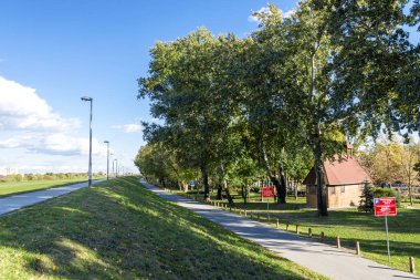 Güneşli bir günde güzel ağaçlarla kaplı Bundek şehir parkı boyunca uzun bir patika, Zagreb ve Hırvatistan