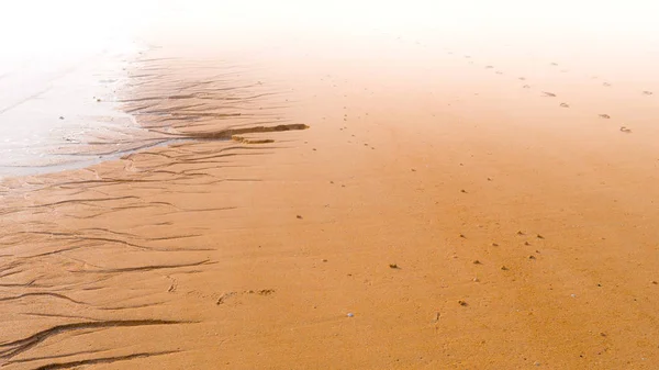 沙滩上的脚印 逐渐消失在雾蒙蒙的地平线上 — 图库照片