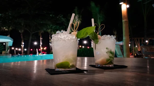 Tropische Cocktails mit viel Eis am beleuchteten Pool in der Nacht — Stockfoto