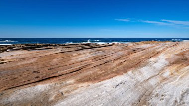 Royal National Park bir plajda pürüzsüz turuncu kaya oluşumları 