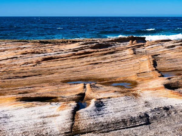 Pietrele portocalii netede și marea albastră strălucitoare din Australia — Fotografie, imagine de stoc