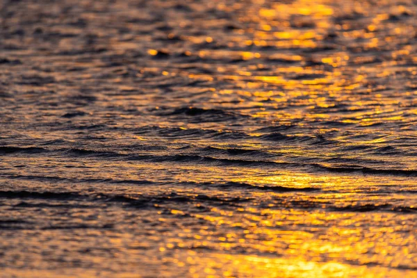 Deniz dalgaları üzerinde gün batımının güzel altın renkleri.