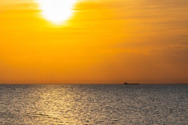 Ufukta güneş doğarken yelken bir kargo gemisi.