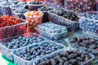 Plastik kaplarda depolanan yeşil markette taze farklı meyveler. Doğal organik gıda maddeleri sağlıklı beslenmesi için. Kutusunda lezzetli taze çilek
