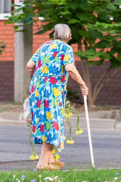 有花的老妇人在街道上行走 — 图库照片