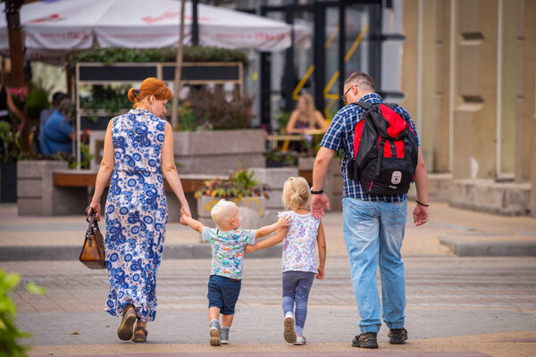 Russia, Rostov on Don, September 09, 2018: Happy family walk with two cute blondy kids on street of city.