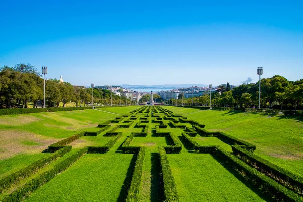 View of the labyrinth of Eduardo VII park and gardens, the largest park in the center of Lisbon and Tagus river in the background, in Lisbon, Portugal — Stock Photo, Image