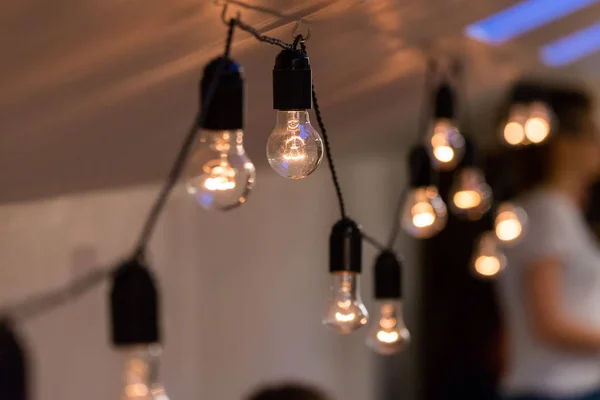 Vista de cerca de la lámpara de luz decorativa vintage que brilla en el techo en el interior. Lámparas transparentes brillando con luz cálida —  Fotos de Stock