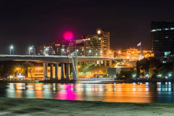 Sandy beach and bridge over the river and night city on the background. — Stock Photo, Image