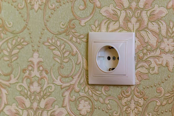 Electric socket on a wall with wallpaper