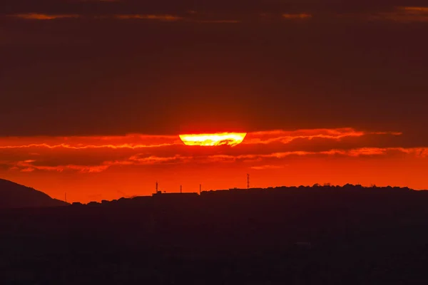 Sol rojo al atardecer bajo las nubes sobre el horizonte. Imagen dramática épica del cielo — Foto de Stock