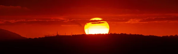 Sol rojo al atardecer bajo las nubes sobre el horizonte. Imagen dramática épica del cielo — Foto de Stock